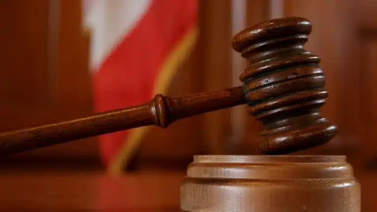 Judge's wooden gavel striking the sound block in a courtroom setting.