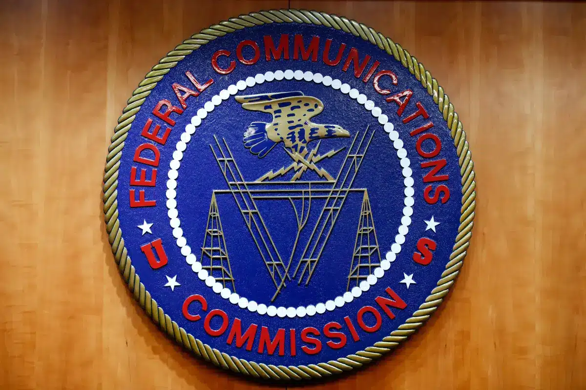 Circular seal of the Federal Communications Commission (FCC) on a wooden background, blue center with red text around the edge.