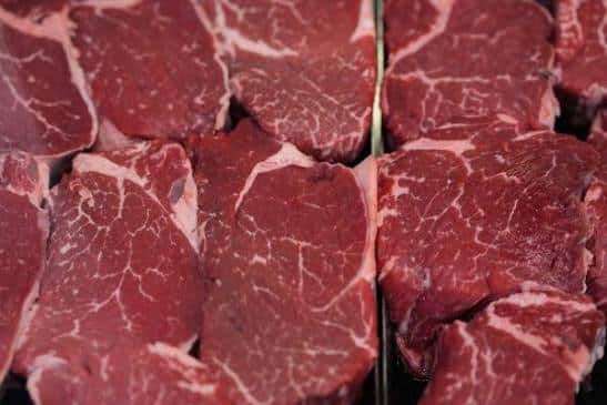 Close-up of raw beef steaks with white marbling arranged in a tray.