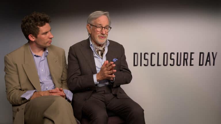 Two men in business attire sit side by side in an interview setting, with a backdrop reading DISCLOSURE DAY; the older man on the right speaks with his hands clasped.