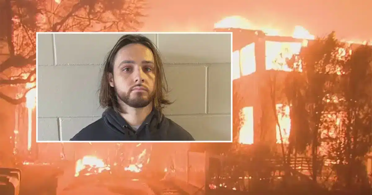 Mugshot-style portrait of a man with shoulder-length hair and beard, inset on a blazing building fire graphic.