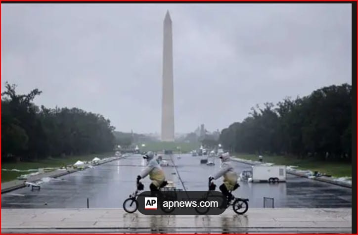Two people ride small motorcycles on a wet, reflective pavement with the Washington Monument in the distance.