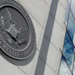 Seal of the U.S. Securities and Exchange Commission on a stone wall beside a glass office building exterior surface.