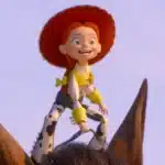 Cowgirl Jessie from Toy Story riding a brown horse against a clear sky, smiling with red hat and yellow accents on her outfit.