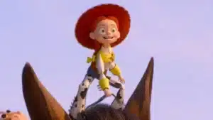 Cowgirl Jessie from Toy Story riding a brown horse against a clear sky, smiling with red hat and yellow accents on her outfit.