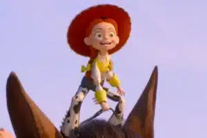 Cowgirl Jessie from Toy Story riding a brown horse against a clear sky, smiling with red hat and yellow accents on her outfit.
