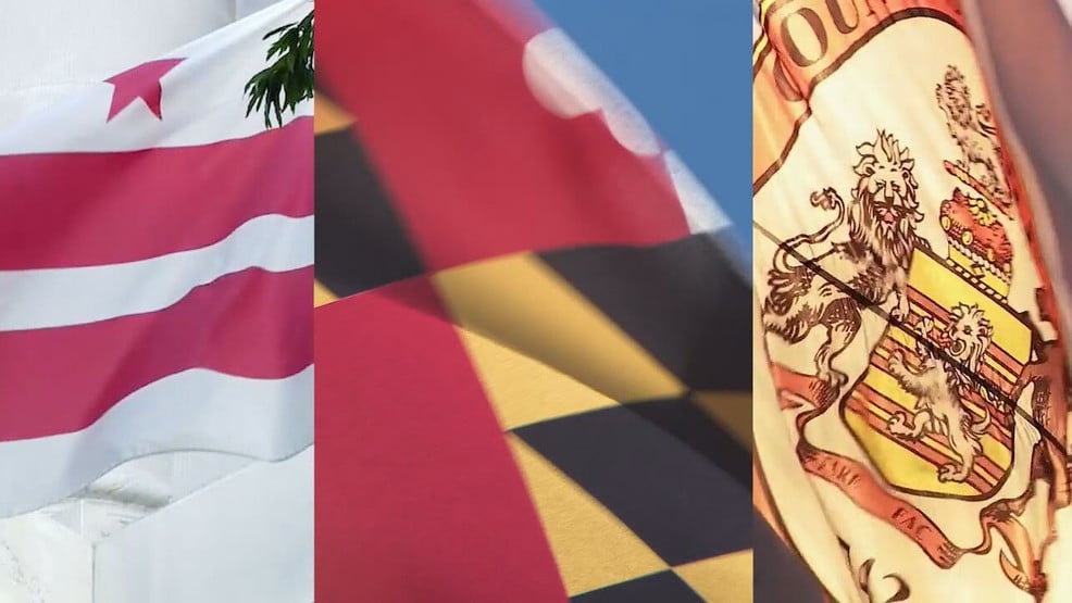 Three flags fluttering side by side in the wind: left has pink and white stripes, center shows a red flag with dark shapes, right displays a heraldic flag with a coat of arms.