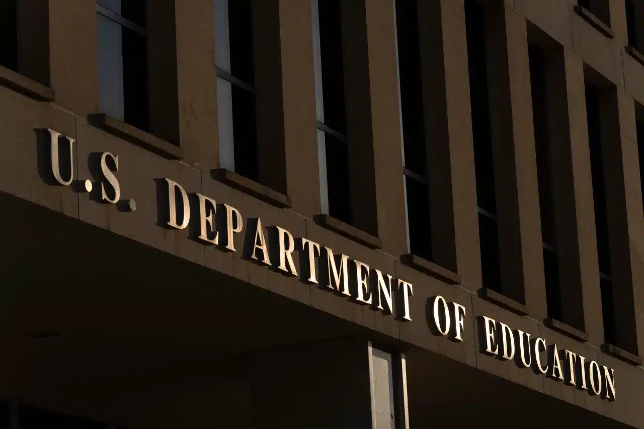 Facade of a government building with the illuminated sign 'U.S. Department of Education' along the entrance.