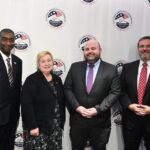 Members of the U.S. Election Assistance Commission standing in front of an EAC seal backdrop