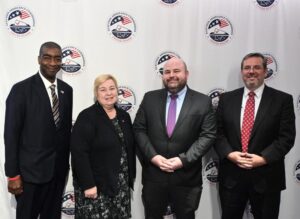 Members of the U.S. Election Assistance Commission standing in front of an EAC seal backdrop