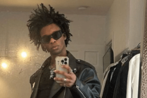 Person wearing sunglasses and a leather jacket takes a mirror selfie in a clothing store.