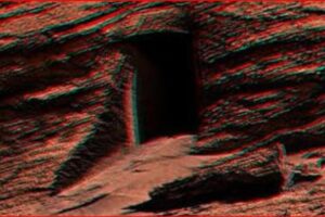 Rocky desert terrain with a dark cave opening carved into the red rock wall (anaglyph 3D effect).