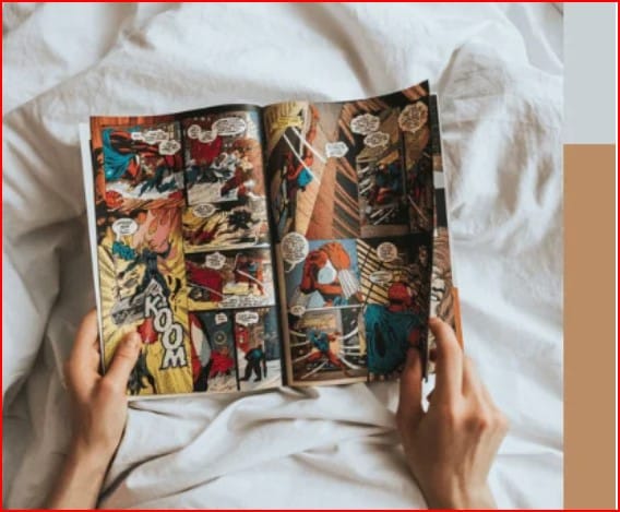 Person's hands hold open a colorful comic book laid on white sheets, panels show superheroes in action.