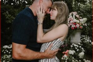 Couple embracing and about to kiss in a garden with pink and white flowers in the background.