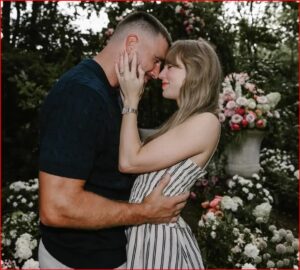 Couple embracing and about to kiss in a garden with pink and white flowers in the background.