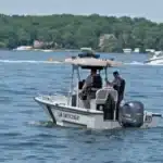 Small patrol boat labeled 'Law Enforcement' with two officers on board patrolling a lake.