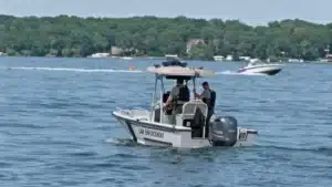 Small patrol boat labeled 'Law Enforcement' with two officers on board patrolling a lake.