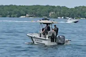 Small patrol boat labeled 'Law Enforcement' with two officers on board patrolling a lake.