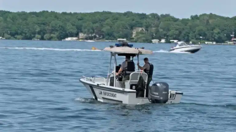 Small patrol boat labeled 'Law Enforcement' with two officers on board patrolling a lake.