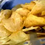 Close-up of salted potato chips inside an open bag, piled together and ready to eat.