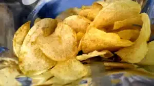 Close-up of salted potato chips inside an open bag, piled together and ready to eat.