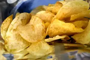 Close-up of salted potato chips inside an open bag, piled together and ready to eat.