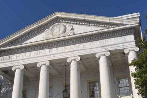 White neoclassical building with six large columns and a triangular pediment reading ‘Hartford Fire Insurance Company’.