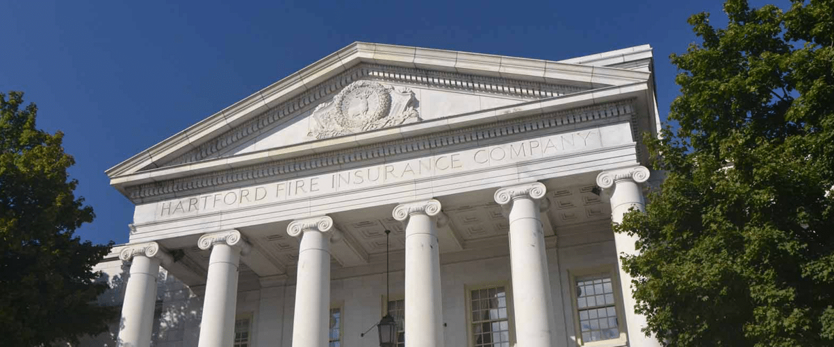 White neoclassical building with six large columns and a triangular pediment reading ‘Hartford Fire Insurance Company’.