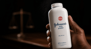 White Johnson’s baby powder bottle held in a dark setting, with a blurred scale of justice in the background.