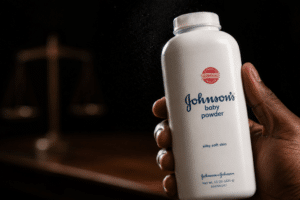 White Johnson’s baby powder bottle held in a dark setting, with a blurred scale of justice in the background.