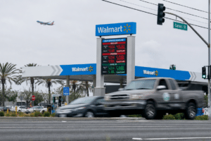 Walmart gas station with price board and multiple cars at a street intersection under cloudy skies