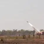 U.S. Army HIMARS launcher firing an ATACMS missile during a military exercise.