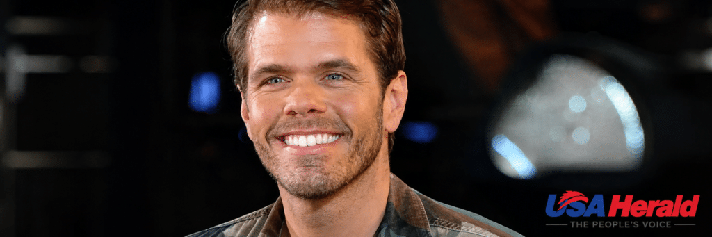 Close-up portrait of a smiling man in a plaid shirt, dark background, with the USA Herald logo in the lower right corner.