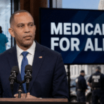 Hakeem Jeffries stands between health care workers and ICE officers beneath a Medicare for All question