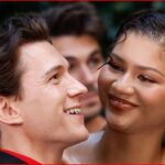 Man and woman smiling at each other in an outdoor setting, close-up portrait.