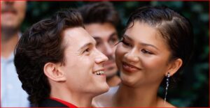 Man and woman smiling at each other in an outdoor setting, close-up portrait.