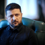 Man with short dark hair and trimmed beard sits in a green office chair, looking to the side in a thoughtful pose.