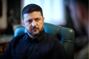 Man with short dark hair and trimmed beard sits in a green office chair, looking to the side in a thoughtful pose.
