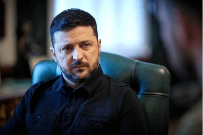Man with short dark hair and trimmed beard sits in a green office chair, looking to the side in a thoughtful pose.
