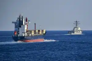 A U.S. Navy destroyer escorts a merchant vessel through the Strait of Hormuz.