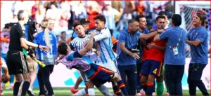 Soccer players and staff involved in a scuffle on the field, grabbing and pushing near the goal area of a match in progress.