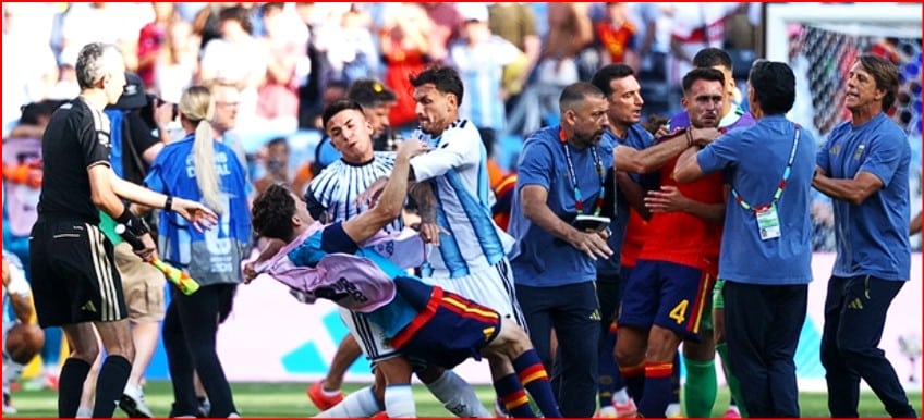 Soccer players and staff involved in a scuffle on the field, grabbing and pushing near the goal area of a match in progress.