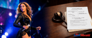 Female singer performing on stage, holding a microphone, with a judge's gavel and legal documents visible on a desk to the right.
