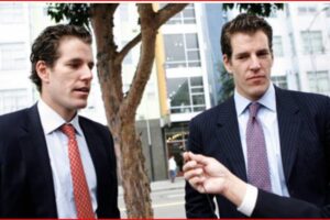Two suited men on a city street being interviewed, a microphone held toward them by a person off-camera