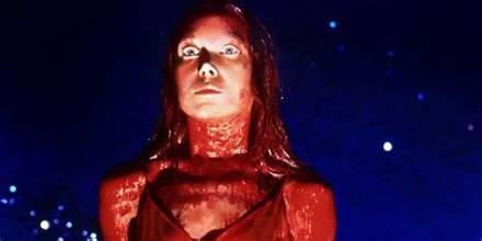 Woman with red lighting on face and neck, wide-eyed expression, looking upward against a dark blue, speckled background.
