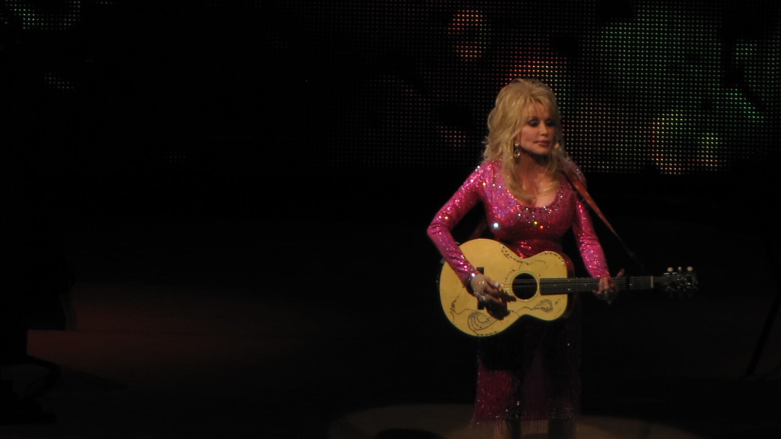 Dolly Parton performs onstage with her guitar at Wolf Trap in 2011.