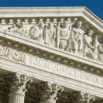 US Supreme Court building façade with sculpted frieze and the inscription 'EQUAL JUSTICE UNDER LAW' beside a waving American flag