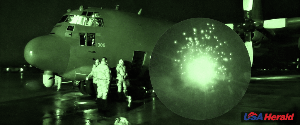 C-130 military transport on the tarmac at night with crew loading under green night-vision lighting