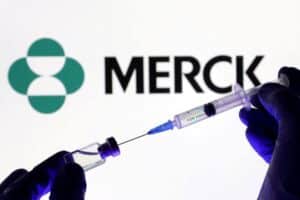 Gloved hands hold a syringe and needle in front of the Merck logo, symbolizing vaccination.