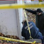 Forensic investigators at a crime scene outside a house, yellow police tape in the foreground.